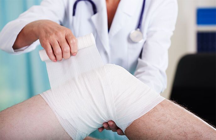 Un médecin panse l'articulation du genou à cause de l'arthrose